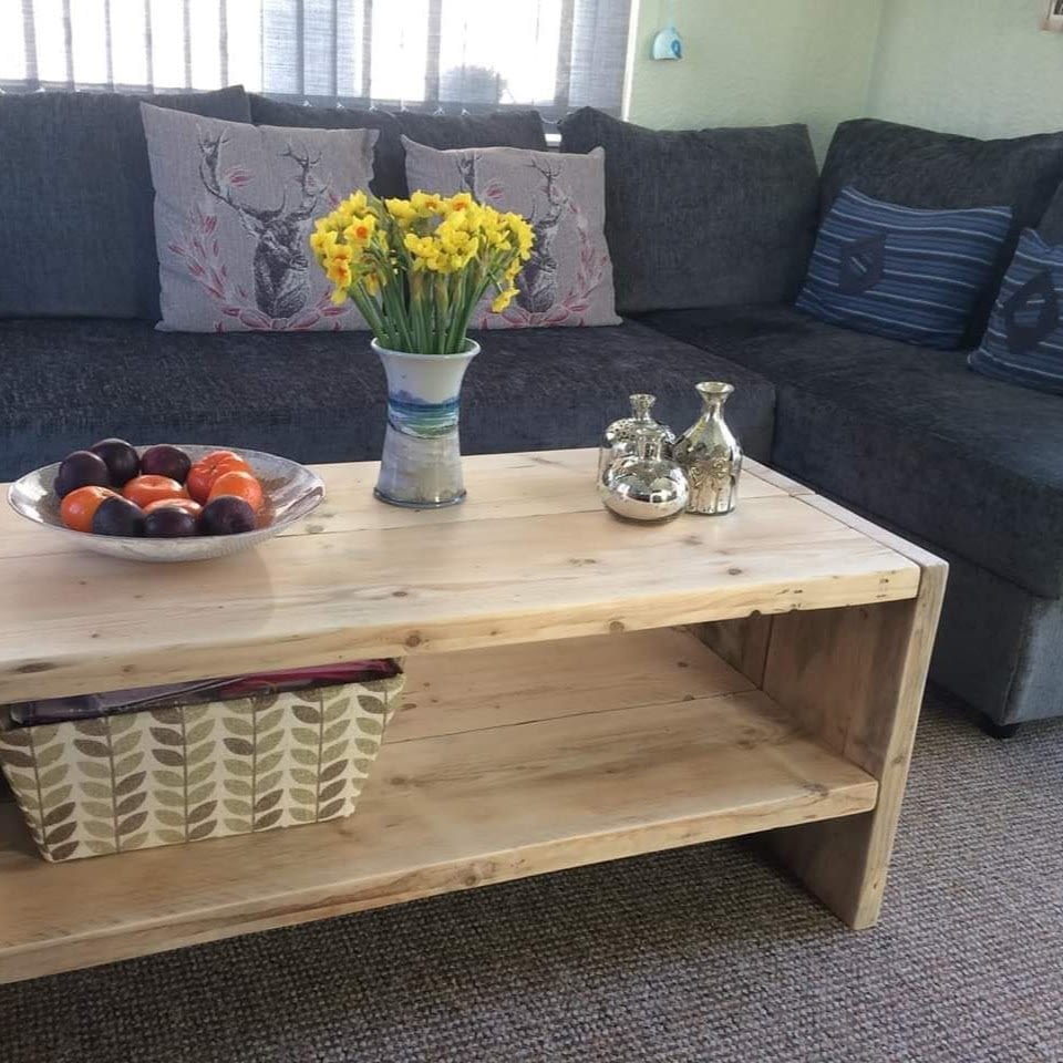 A rustic wooden coffee table with grey sofa